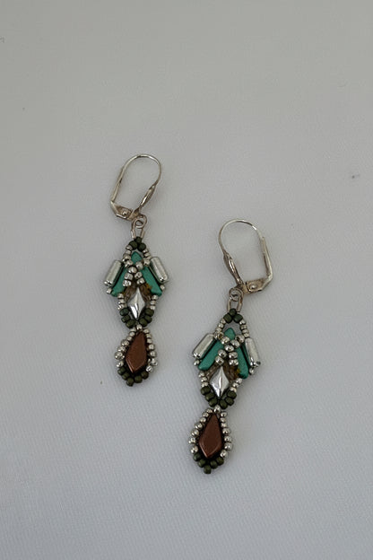 Pair of silver earrings with green and brown beads on a gray background.