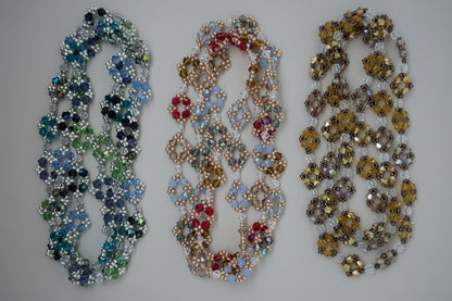 Three beaded necklaces of different colors on a gray background