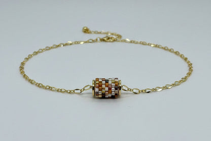 Gold necklace with a beaded woven pendant on a white background