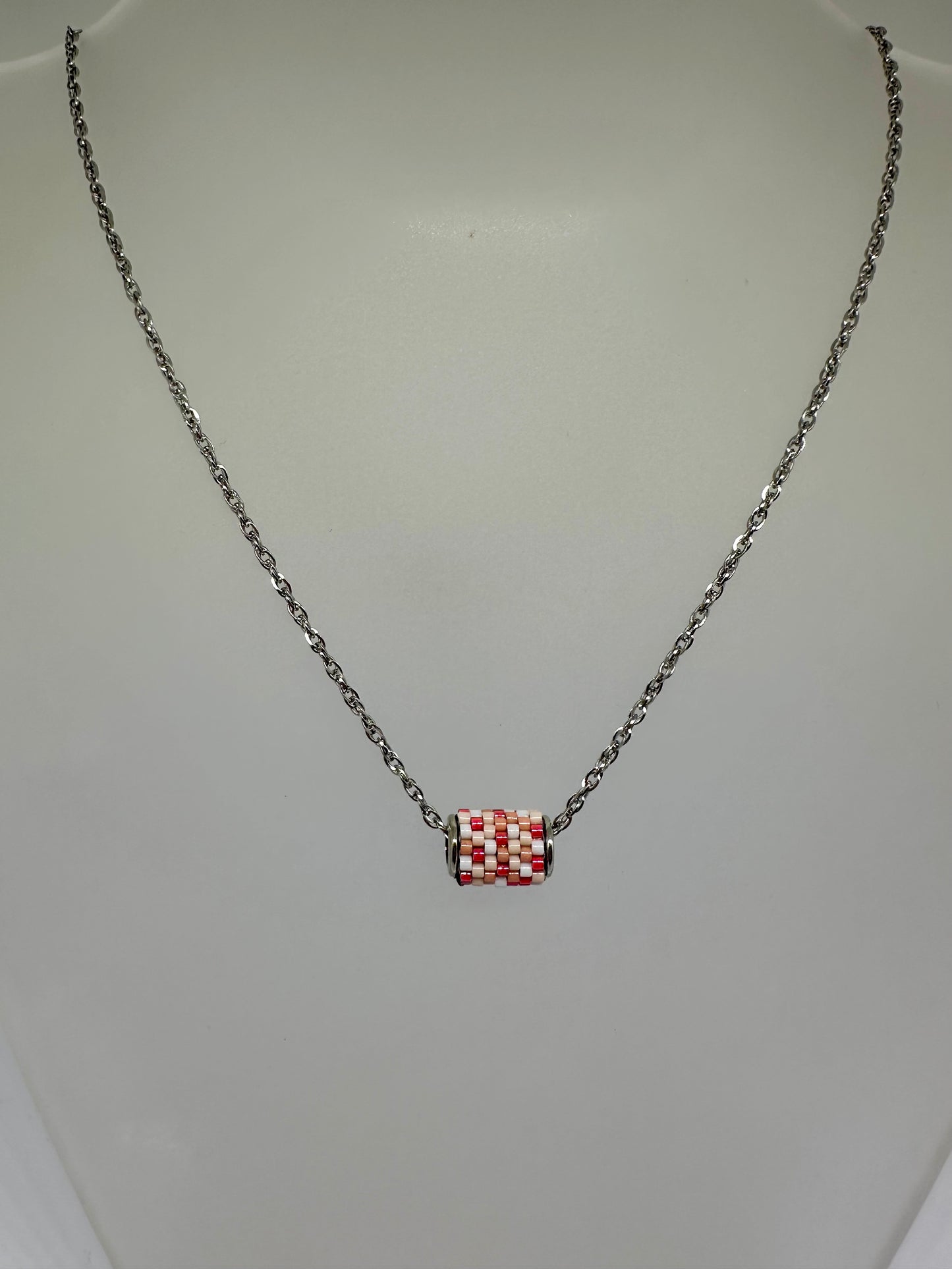 Silver necklace with a beaded woven pendant on a white background
