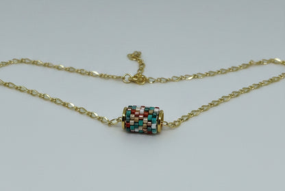 Gold necklace with a beaded woven pendant on a white background