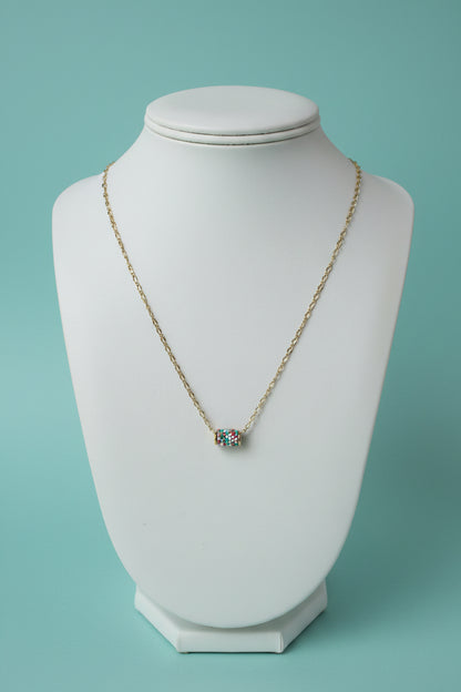 Necklace with a pendant on a white mannequin bust against a teal background