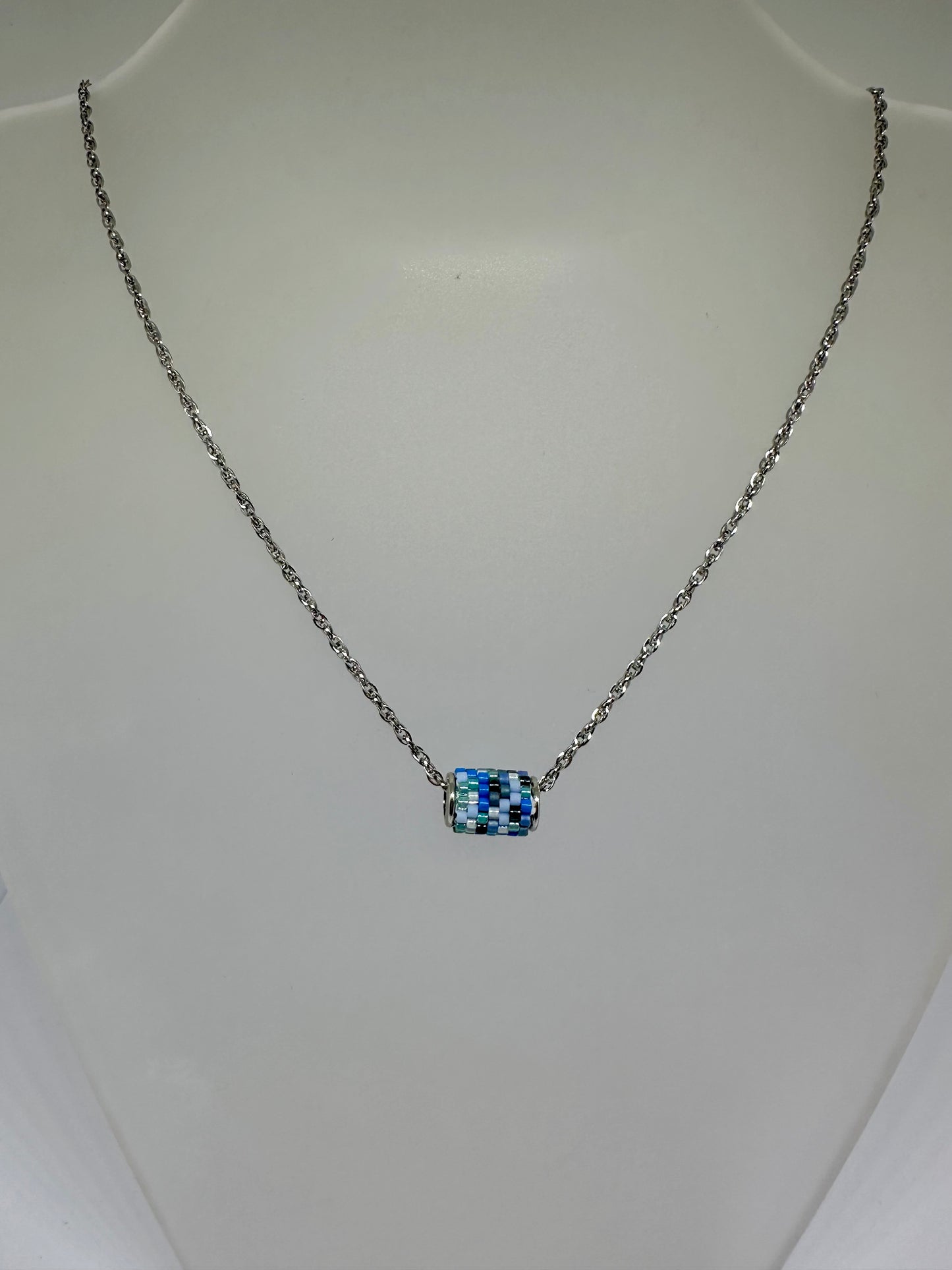 Silver necklace with a beaded woven pendant on a white background
