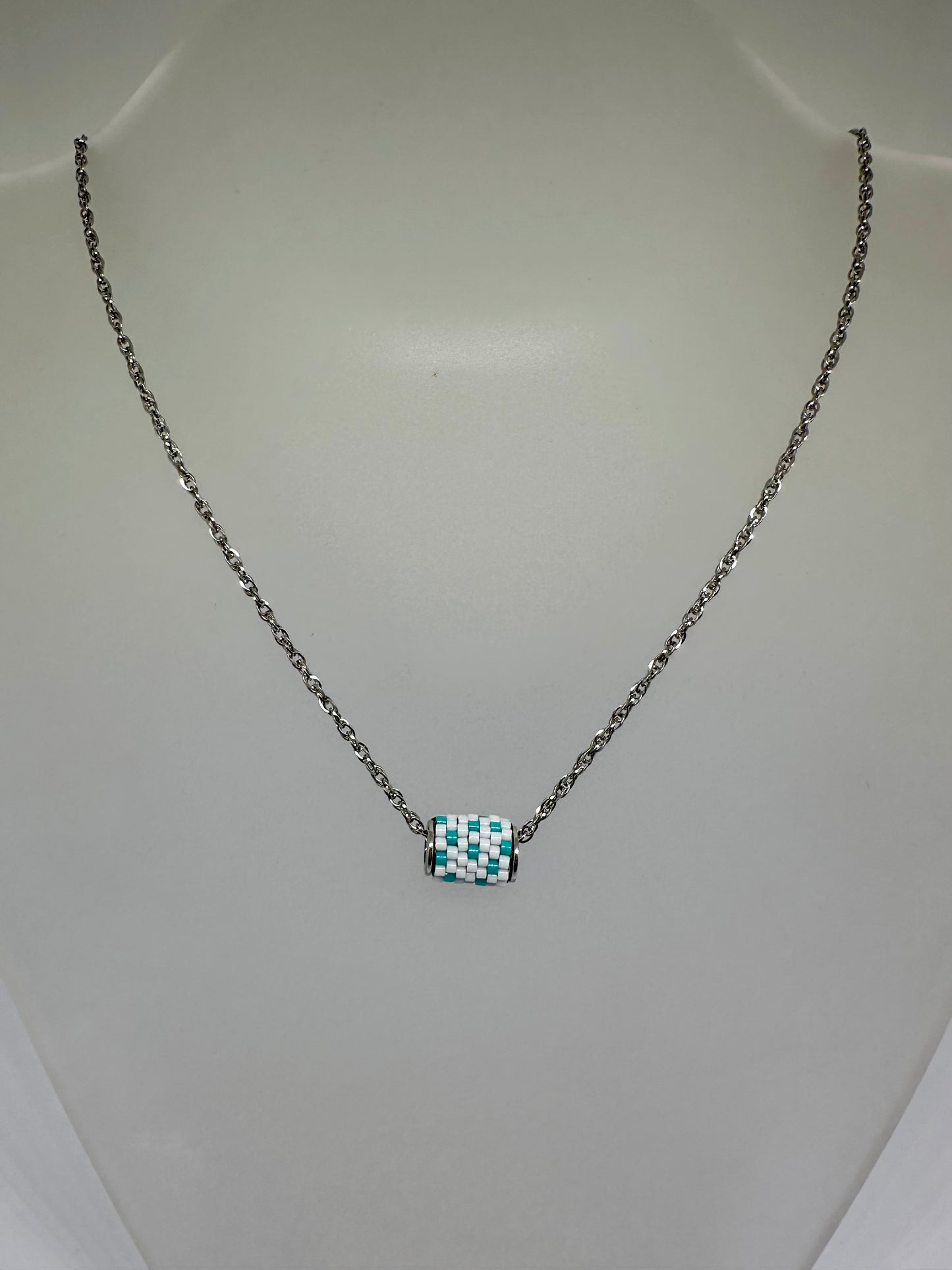 Silver necklace with a beaded woven pendant on a white background