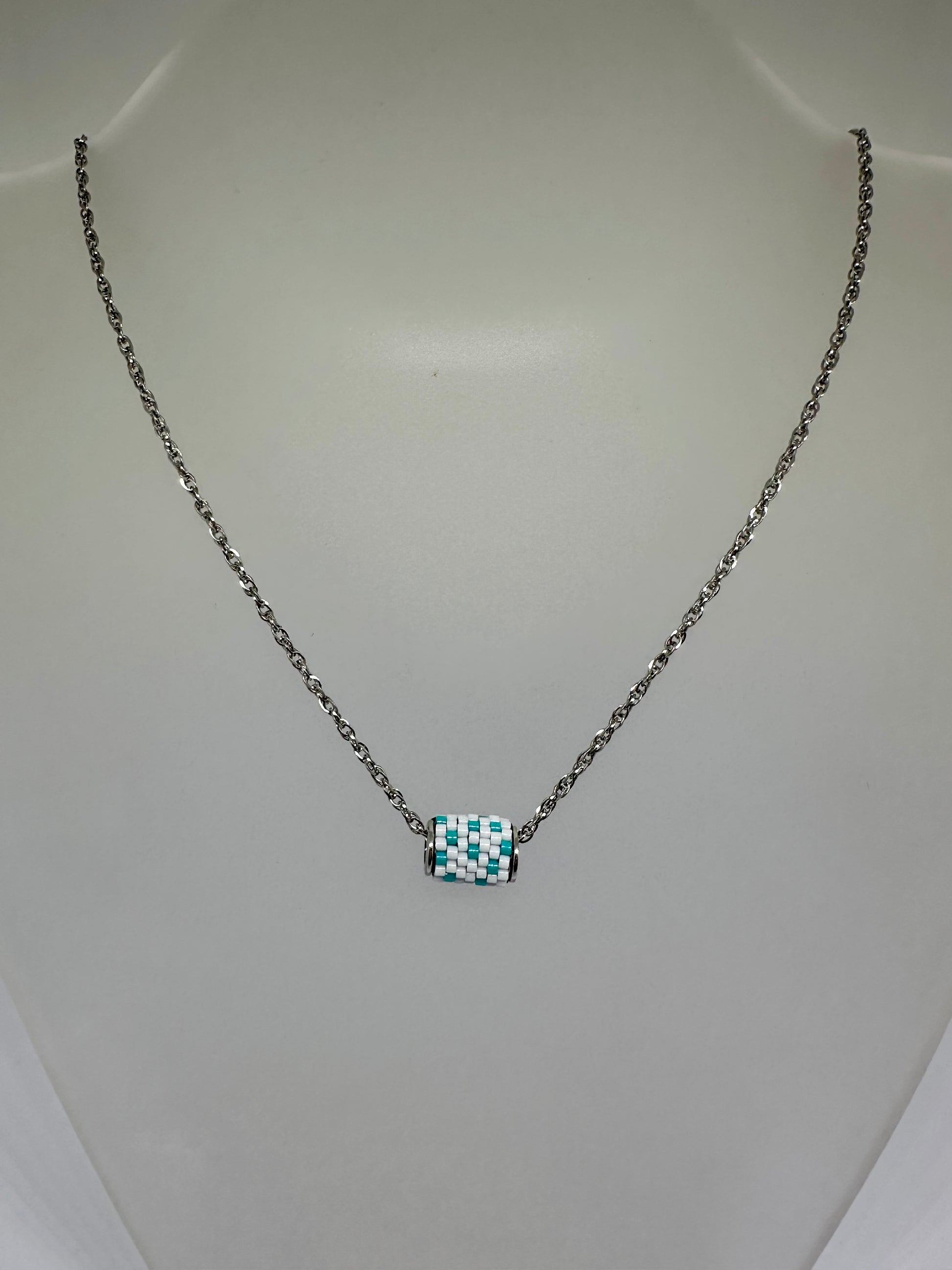 Silver necklace with a beaded woven pendant on a white background