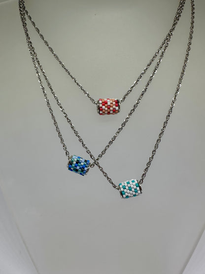 Three necklaces with colorful beaded pendants on a light gray background