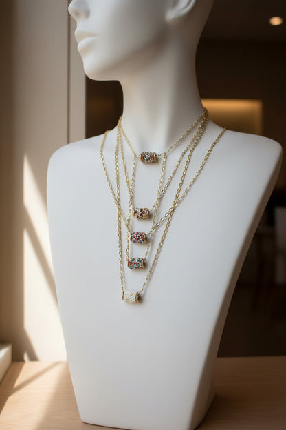 Mannequin wearing multiple gold necklaces with small pendants on a neutral background